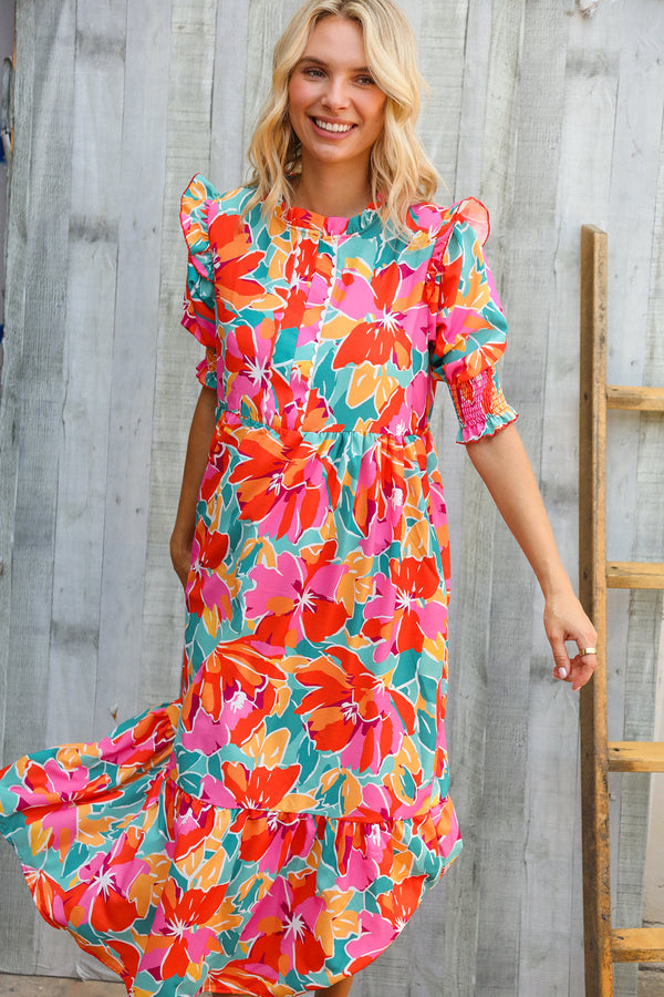Woman wearing a colorful floral dress against a wooden background