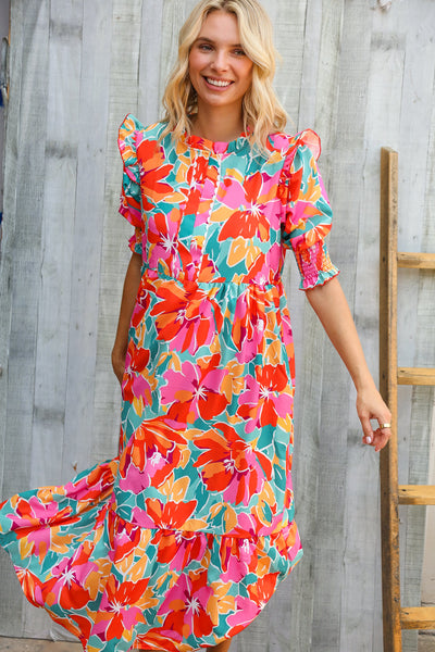 Woman wearing a colorful floral dress against a wooden background