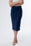 A model wearing a midi length navy pencil skirt with a stretchy elastic waist, paired with beige ankle strap sandals.