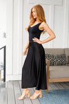 Side view of model in flowing black poly satin maxi skirt with flat front waist