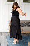 Side view of plus size model in poly satin black maxi skirt with full coverage