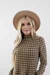 Close up of checkered cocoon modest dress with mock neck, welt pockets, knee-length silhouette, and stretchy knit polyester fabric