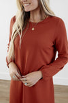 Close up of Rich-toned modest knit dress with long puff sleeves, straight silhouette, and knee-length hem, made from cozy polyester-rayon-spandex blend