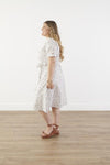 Side view of plus size cotton midi dress with chest pocket, decorative side buttons, elastic waist with sash, and A-line skirt in breathable white fabric
