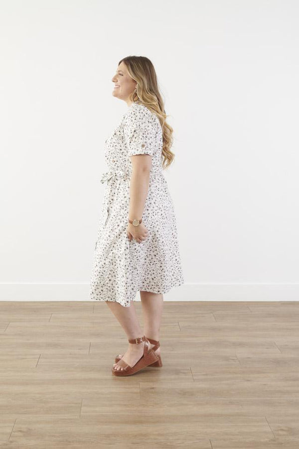 Side view of plus size cotton midi dress with chest pocket, decorative side buttons, elastic waist with sash, and A-line skirt in breathable white fabric