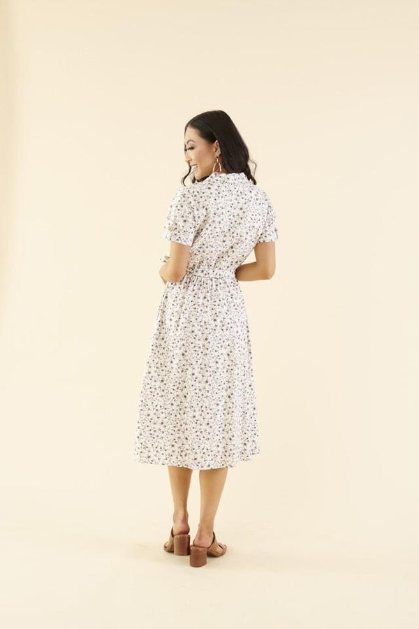 Back of cotton midi dress with chest pocket, decorative side buttons, elastic waist with sash, and A-line skirt in breathable white fabric